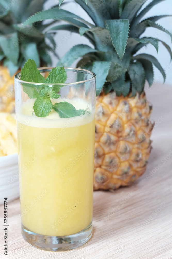 Glass of pineapple juice with some whole pineapple on the background Glass of pineapple juice with some whole pineapple on the background