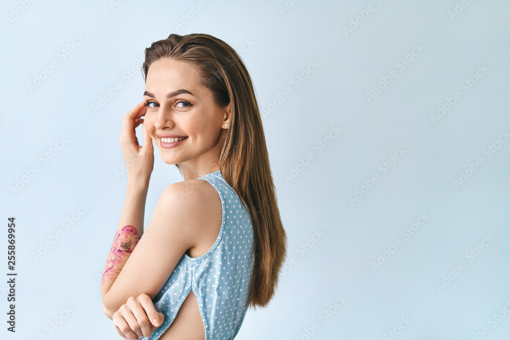 Young smiling beautiful woman posing in blue background with copy space Young smiling beautiful woman posing in blue background with copy space