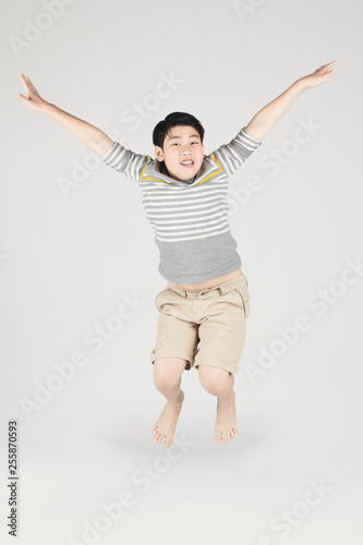 Asian funny child boy jumping on gray background.
