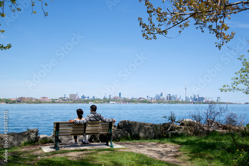Photography couple sitting on the park bench with Toronto as background