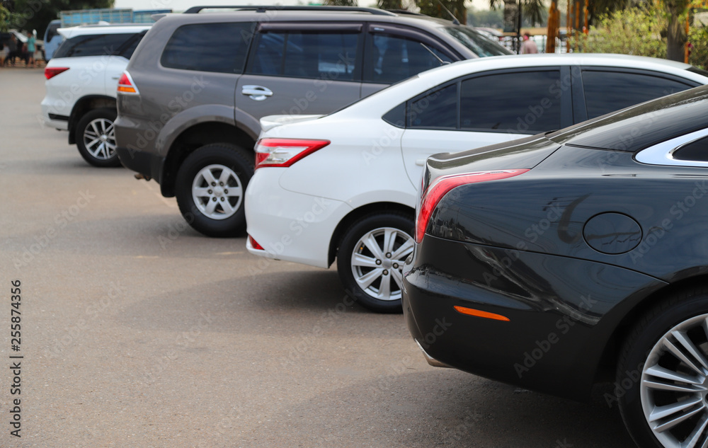 Closeup of back or rear side of black car and other cars parking in parking area in sunny day. 