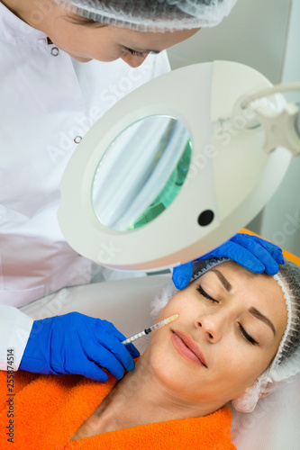 Female doctor doing beauty injection to young woman client