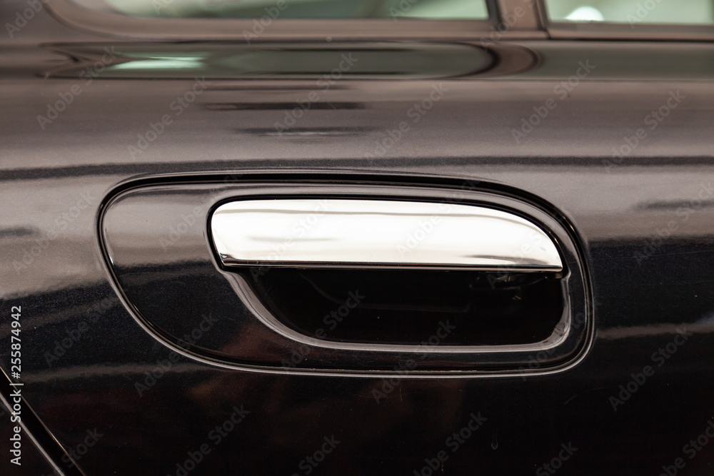 View on closed black front door with handle made from chromium of luxury car after detailing and polishing