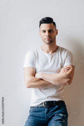 Young handsome man with crossed arms posing on white background