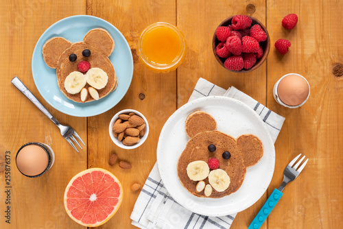 Funny pancakes foor art for kids. Healthy breakfast Table top view on a wooden table. Walrus, dog or bear shaped pancakes decorated with fruits and berries, children meal