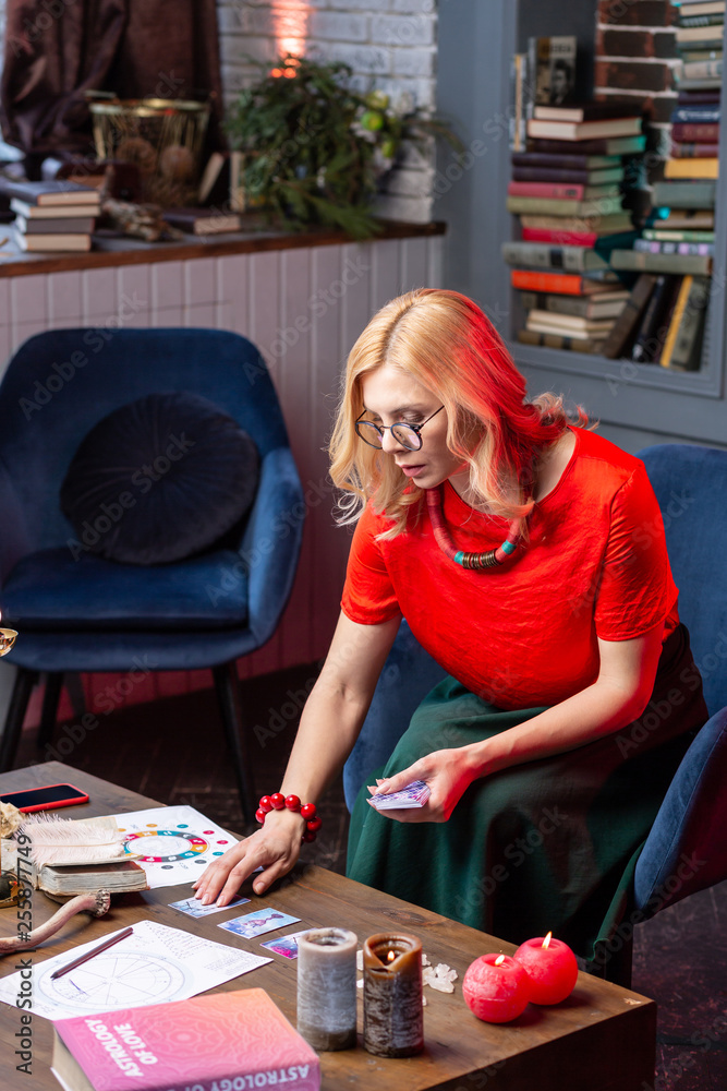 Fototapeta premium Blonde-haired astrologist feeling busy while reading oracle cards
