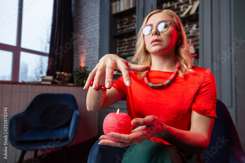 Blonde-haired wisewoman predicting future holding candle in hands photo