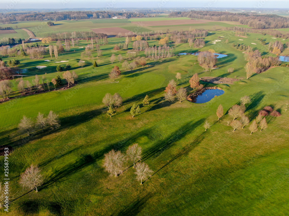 Aerial view of a golf course. Beautiful colorful trees and green course during autumn/winter season in the South of Belgium, Walloon Brabant.