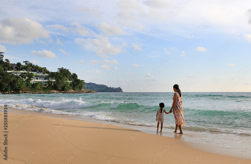 Pregnant mother and daughter walking together on the beach at sunset. Pregnant mother and daughter walking together on the beach at sunset.