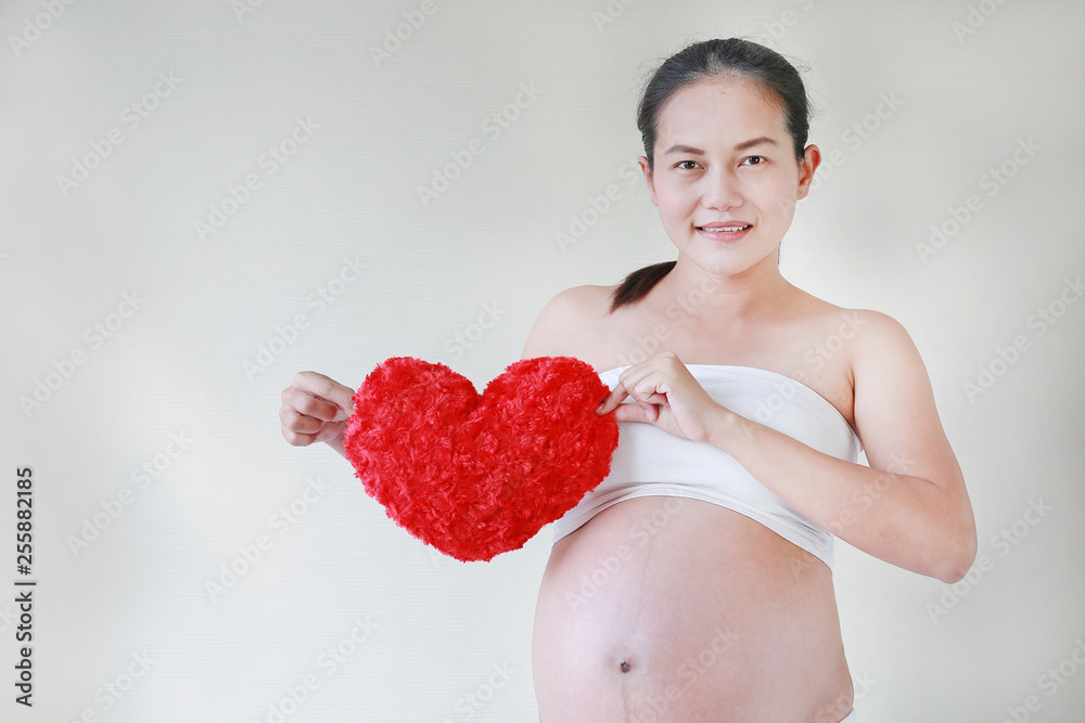 Portrait of pregnant woman holding a red heart pillow near her belly. Portrait of pregnant woman holding a red heart pillow near her belly.