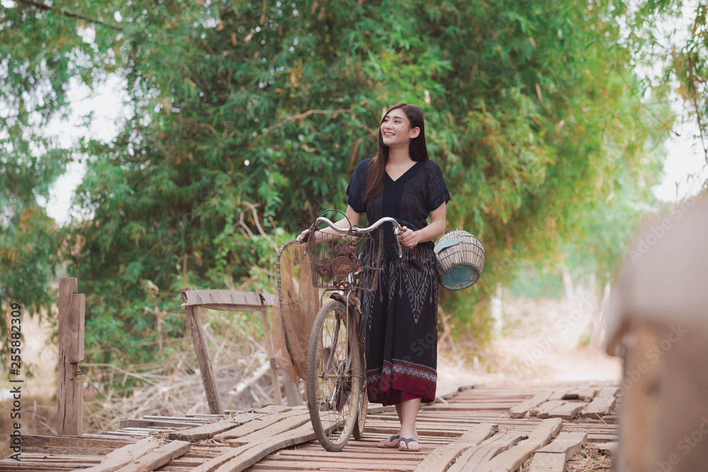 Women wear traditional clothes and bicycles on old wooden bridges.Women and traditional fishing equipment Asian women with beautiful traditional dresses Women wear traditional clothes and bicycles on old wooden bridges.Women and traditional fishing equipment Asian women with beautiful traditional dresses