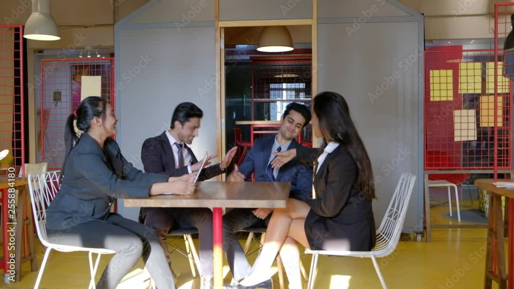 Business meeting between young Indian coworkers in an informal atmosphere as they celebrate their success of their coworker and acknowledge it and bow their heads 