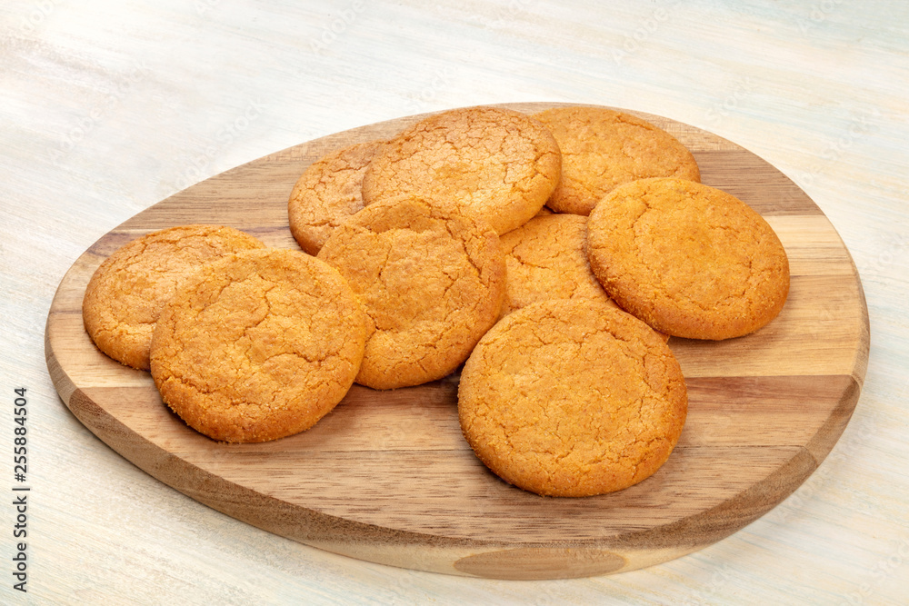 A photo of a heap of gingersnaps on a wooden tray