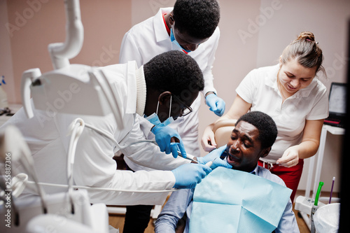 Multiracial dentist doctors team. African american man patient preparing for surgery. Scared face of the patient.