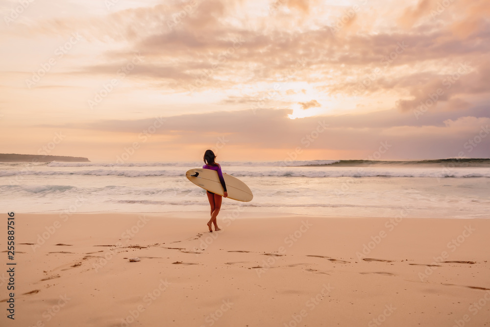 Surfer girl with surfboard on a beach at sunset or sunrise. Surfer girl with surfboard on a beach at sunset or sunrise.