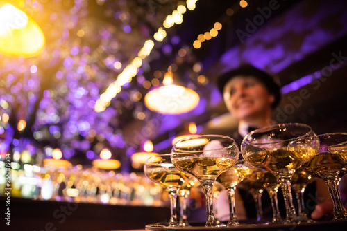 happy waitress holding a tray full of glasses or welcome drinks at an event photo