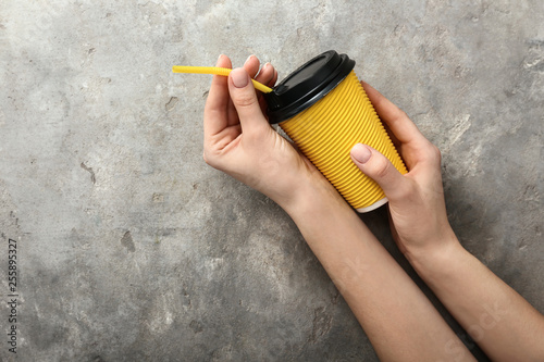 Female hands with cup of coffee on grey background