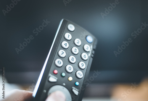 Male hand is holding TV remote control, smart TV.