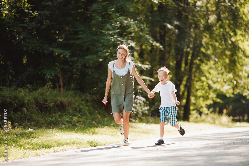 Younger brother and elder sister are running around park, holding hands, having fun, laughing, smiling. Concept Happy family