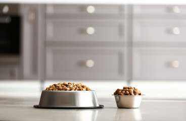 Bowls with dry pet food on floor