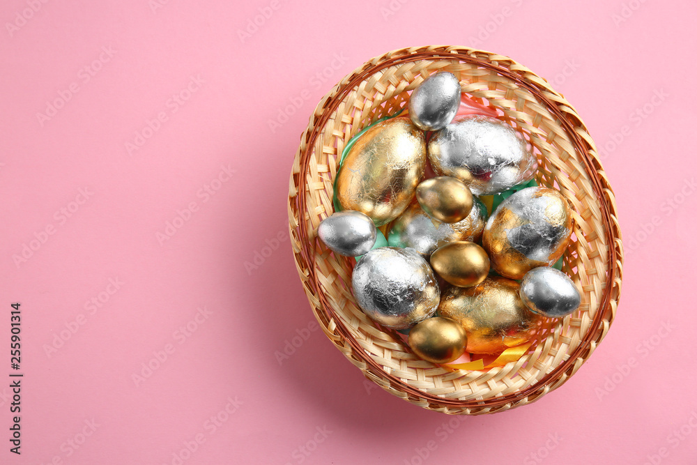 Wicker tray with beautiful Easter eggs on color background Wicker tray with beautiful Easter eggs on color background