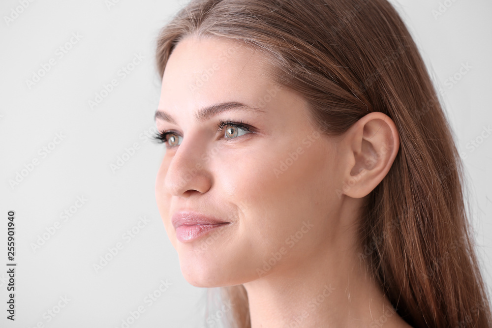 Young woman with beautiful eyelashes on light background