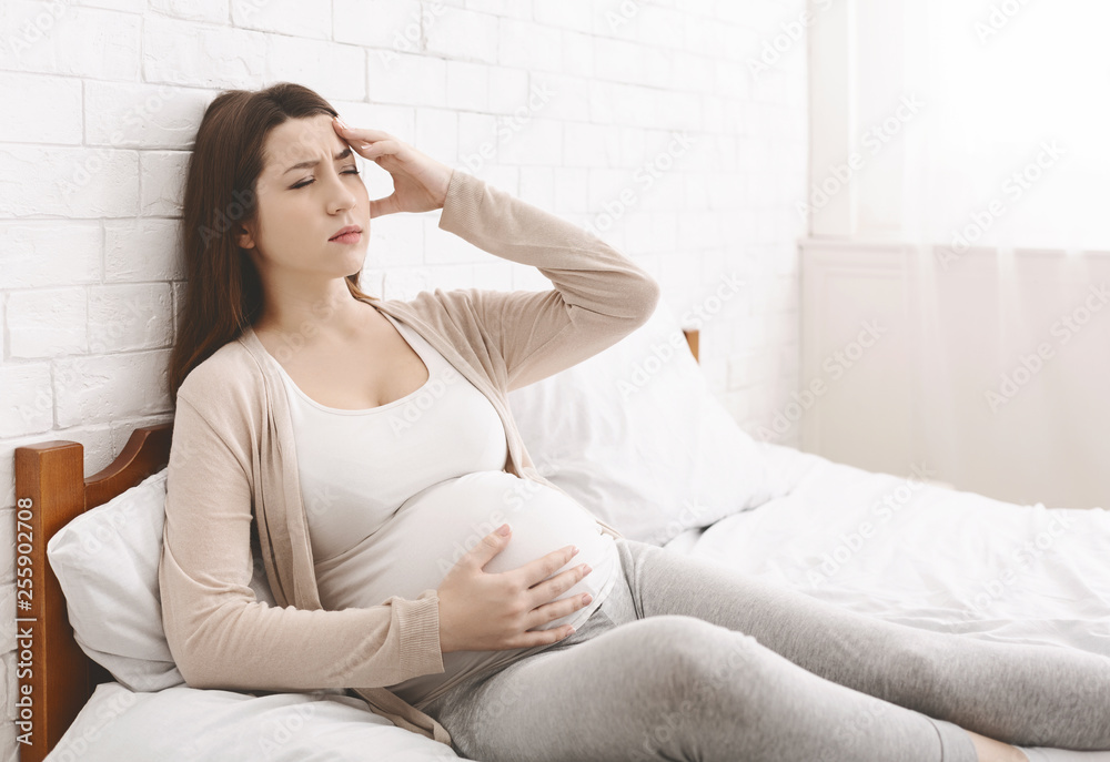 Young pregnant woman suffering from headache or migraine Young pregnant woman suffering from headache or migraine