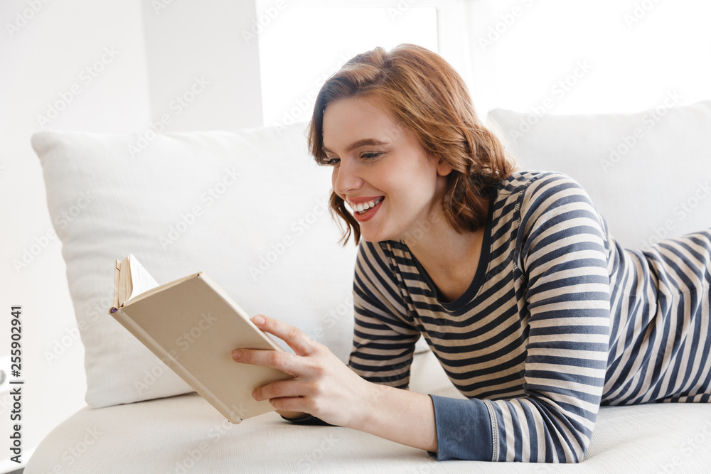 Beautiful smiling young woman relaxing on a couch Beautiful smiling young woman relaxing on a couch