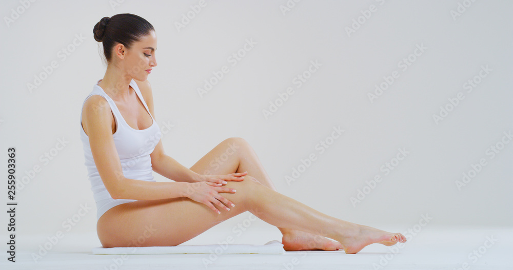 Portrait of young beautiful woman with perfect body touching gently her hairless soft and silky legs after depilation isolated on a white background. Portrait of young beautiful woman with perfect body touching gently her hairless soft and silky legs after depilation isolated on a white background.
