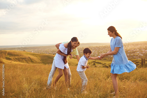 Happy family playing fun on the field at sunset.