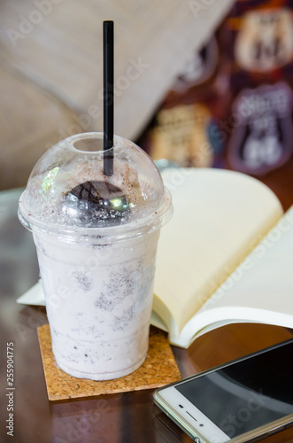 milk chocolate smoothie with open book and smartphone on glass table