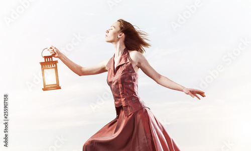 Attractive girl muse with old lantern in hand at summer day
