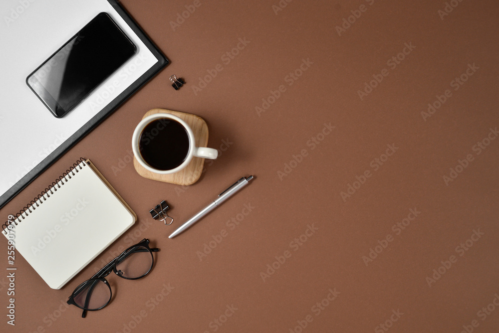 Creative flat lay, top view office table desk. Workspace with blank clip board, office supplies, pen, notepad, smartphone, glasses and coffee cup on a brown background. - obrazy, fototapety, plakaty 