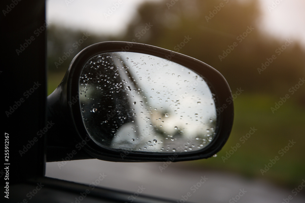 The reflection of road in the side view mirror with raindrops. Travel concept. Bad weather and grey sky. The reflection of road in the side view mirror with raindrops. Travel concept. Bad weather and grey sky.