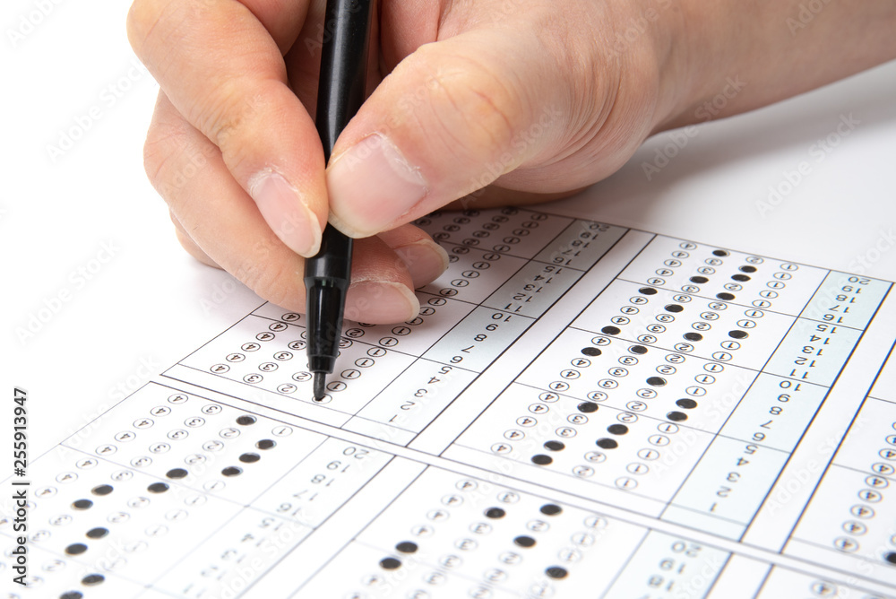 Man is filling OMR sheet handing with pen.