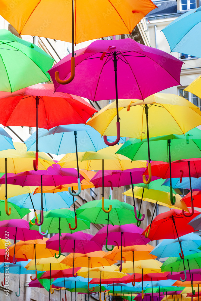 A place in the center of Paris with colorful umbrellas instead of ceiling. Yellow red pink blue green orange. Sunlight coming from the top. Wind is blowing