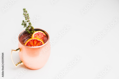 Red oranges cocktail in copper mug (variation of Moscow mule) on the wooden background. Selective focus. Shallow depth of field. photo