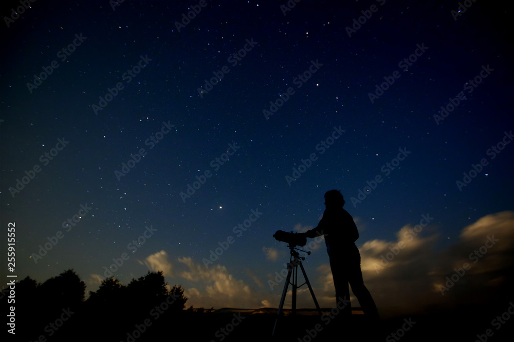 Silhouette of an adult man with a telescope