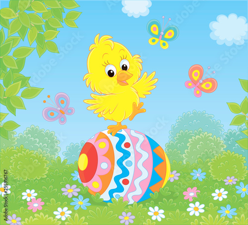 Little yellow Easter Chick dancing on a big colorfully decorated egg on green grass of a lawn on a sunny spring day, vector illustration in a cartoon style