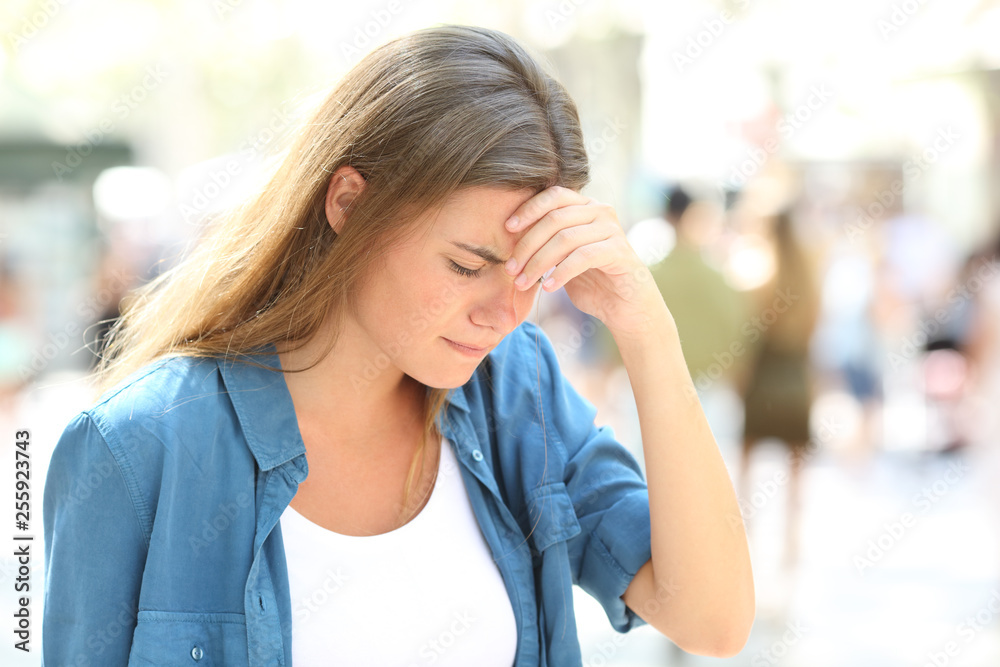Girl suffering headache standing in the street Girl suffering headache standing in the street