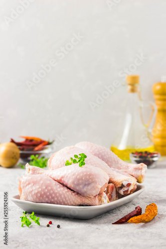 Raw chicken legs, pepper, olive oil on concrete background. Selective focus, space for text.