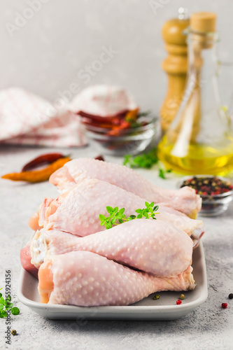 Raw chicken legs,spices and olive oil on concrete background. Top view, space for text.