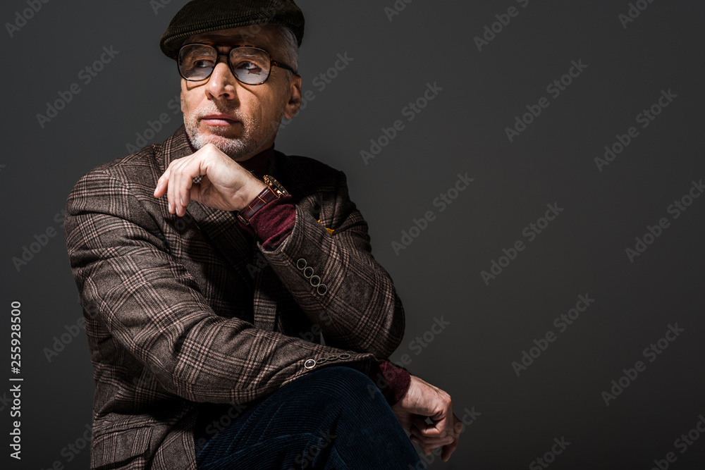 pensive mature man in glasses and cap thinking on grey pensive mature man in glasses and cap thinking on grey