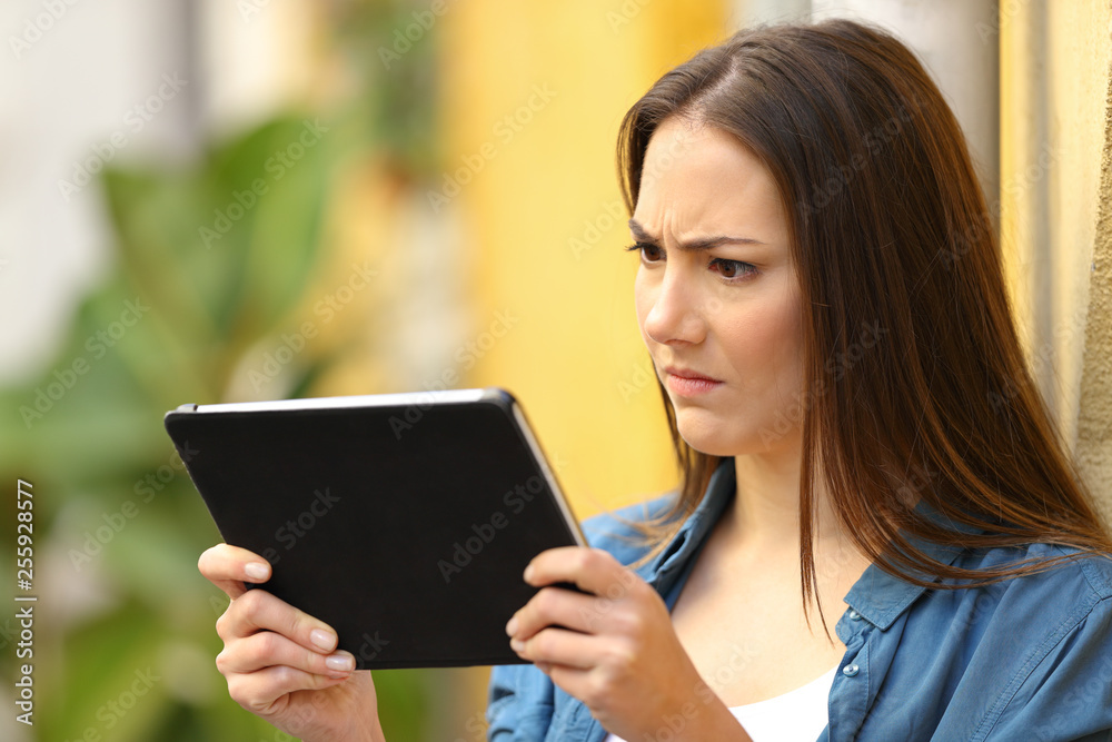 Angry woman checking tablet content in the street Angry woman checking tablet content in the street