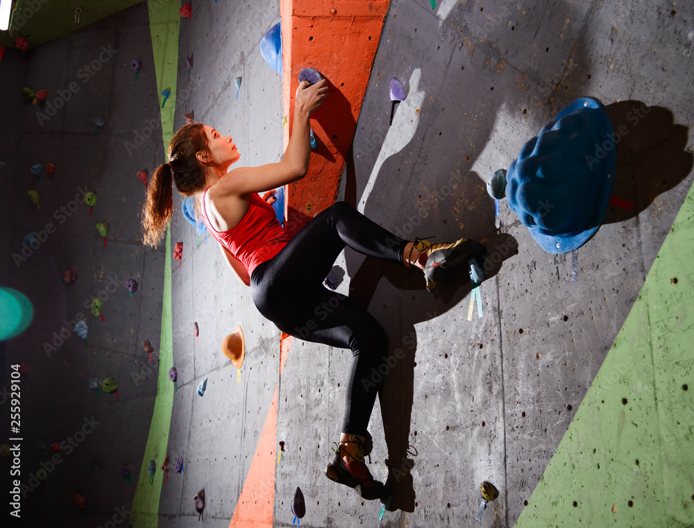 Young Active Woman Bouldering on Colorful Artificial Rock in Climbing Gym. Extreme Sport and Indoor Climbing Concept
