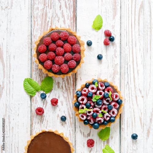 Fotografie Raspberry and blueberry tartlets with chocolate ganache, fresh berries and mint leaves, selective focus
