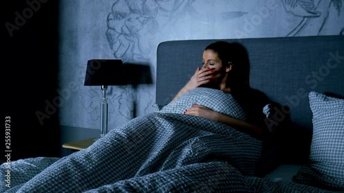 A beautiful young woman in bed going to sleep at night.