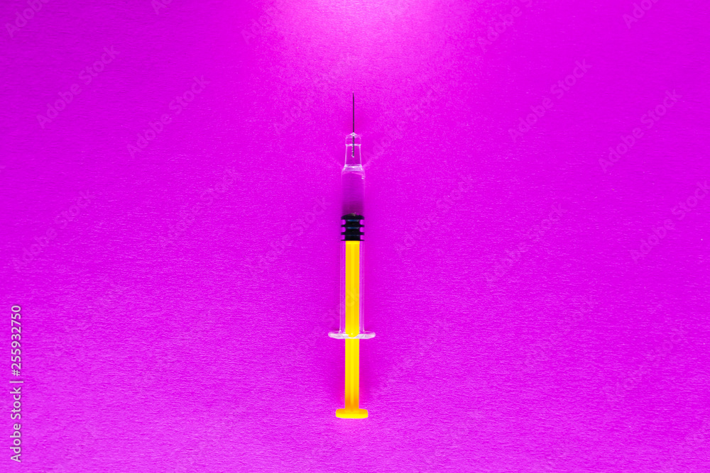 Yellow glass medical syringe over pink background Yellow glass medical syringe over pink background