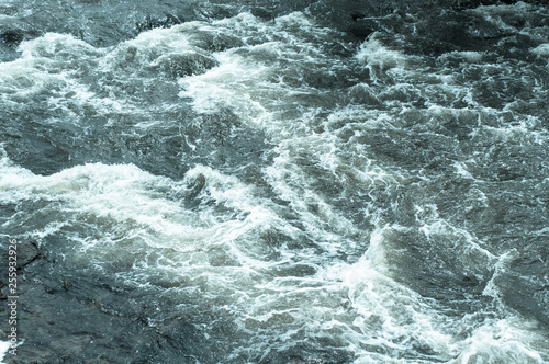 Turbulent stream, fast flowing river with blue water and white foam waves, background, top view