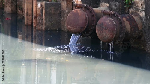 waste water flowing from metal pipe to the river.